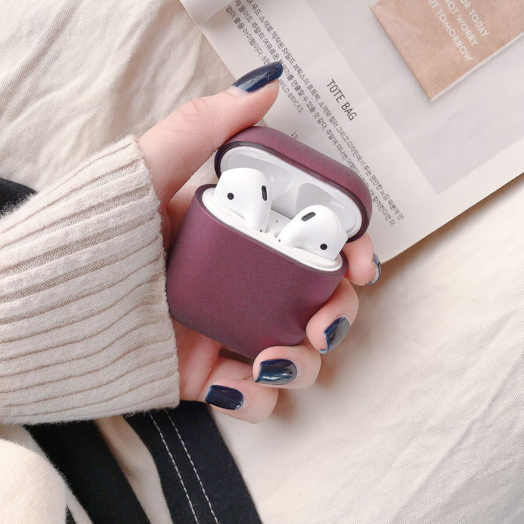 a hand holding a case with white earbuds