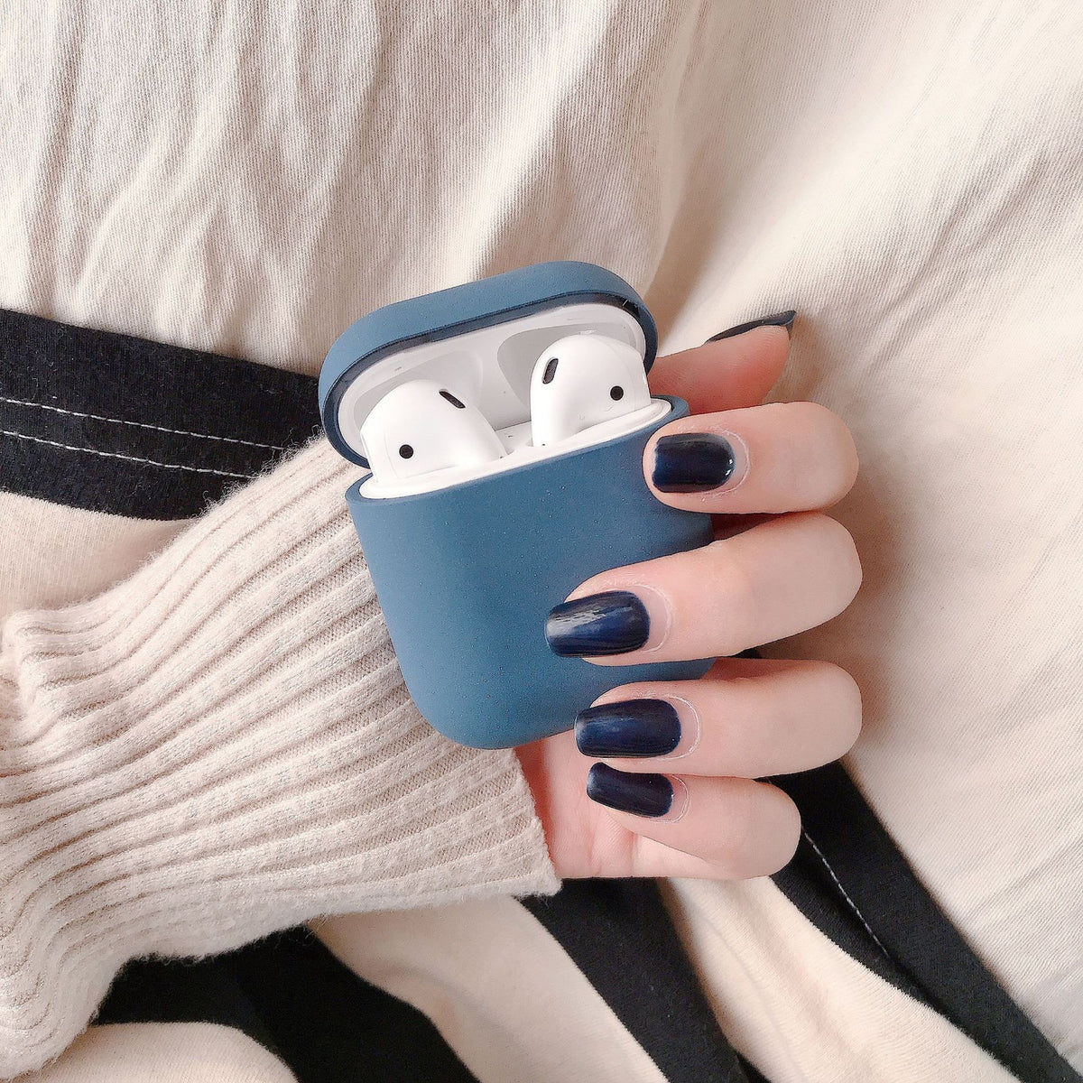 a hand holding a case with white earbuds