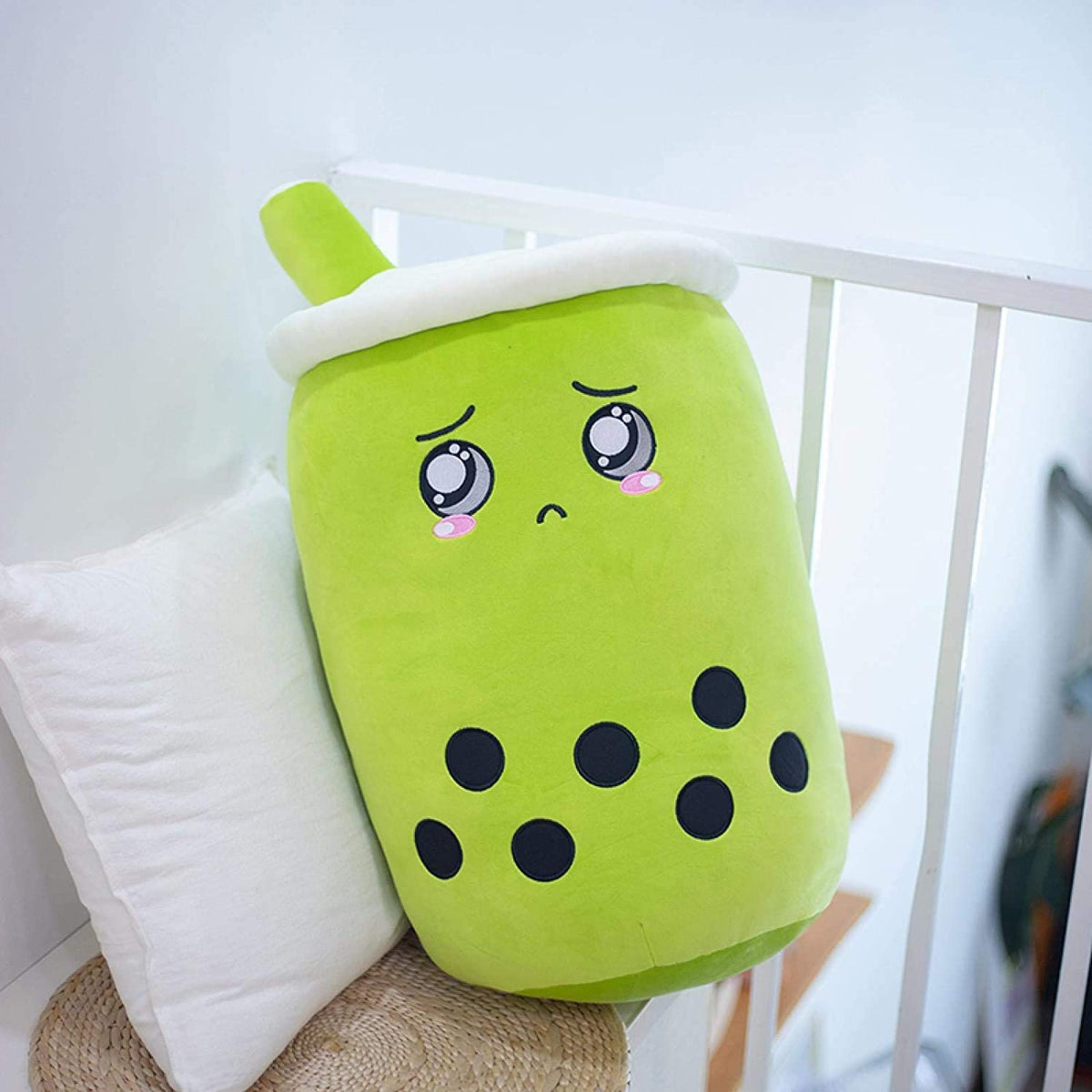 a green soft toy with a face on it