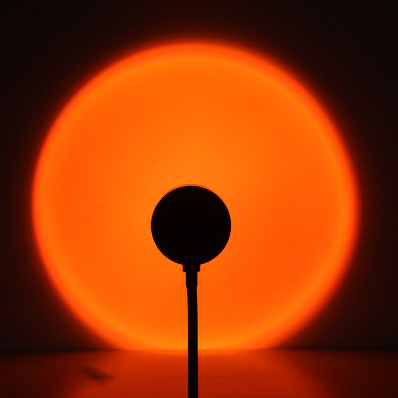 a silhouette of a round object with a bright orange circle in the background
