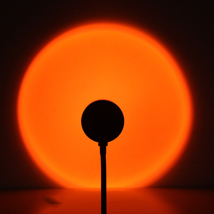 a silhouette of a round object with a bright orange circle in the background