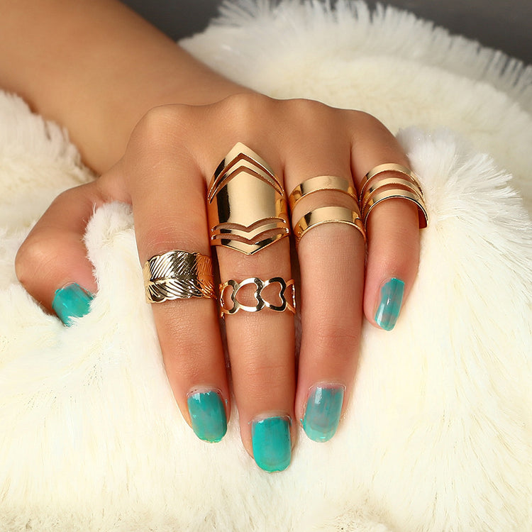 a hand with turquoise painted nails and gold rings