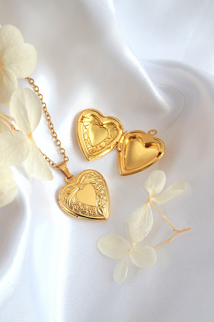 a gold heart shaped locket necklace and pendant on a white cloth