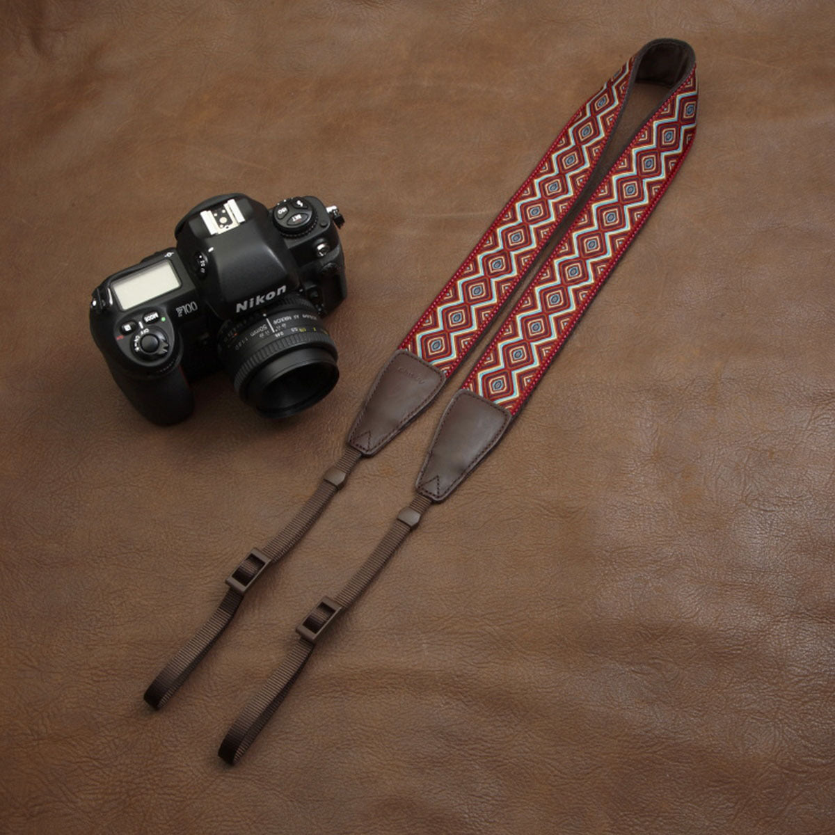 a camera and strap on a leather surface