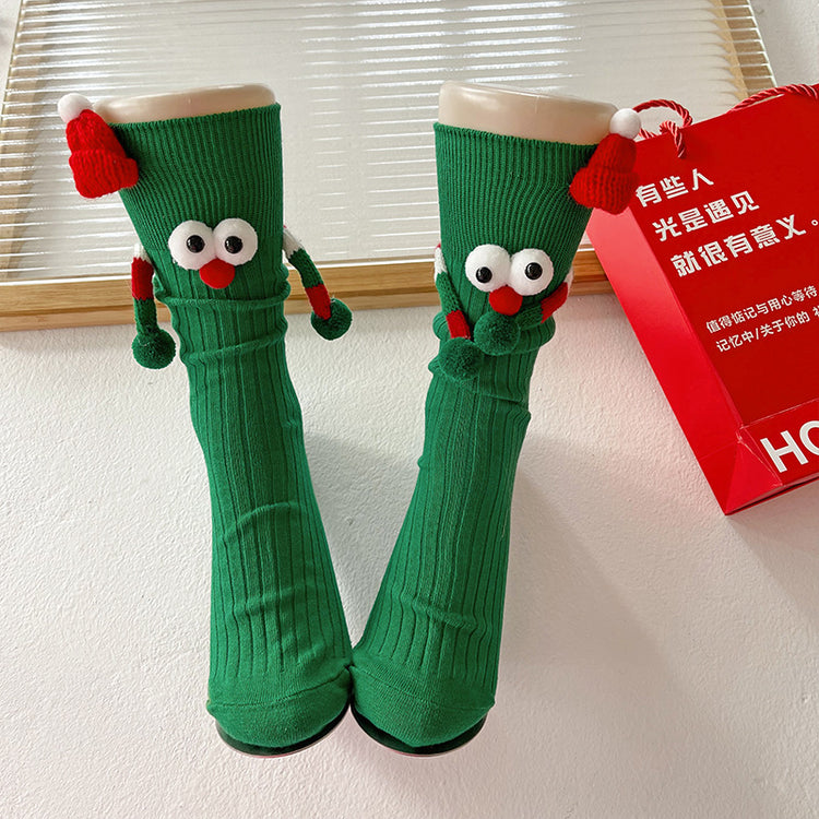 a pair of green socks with eyes and red hats