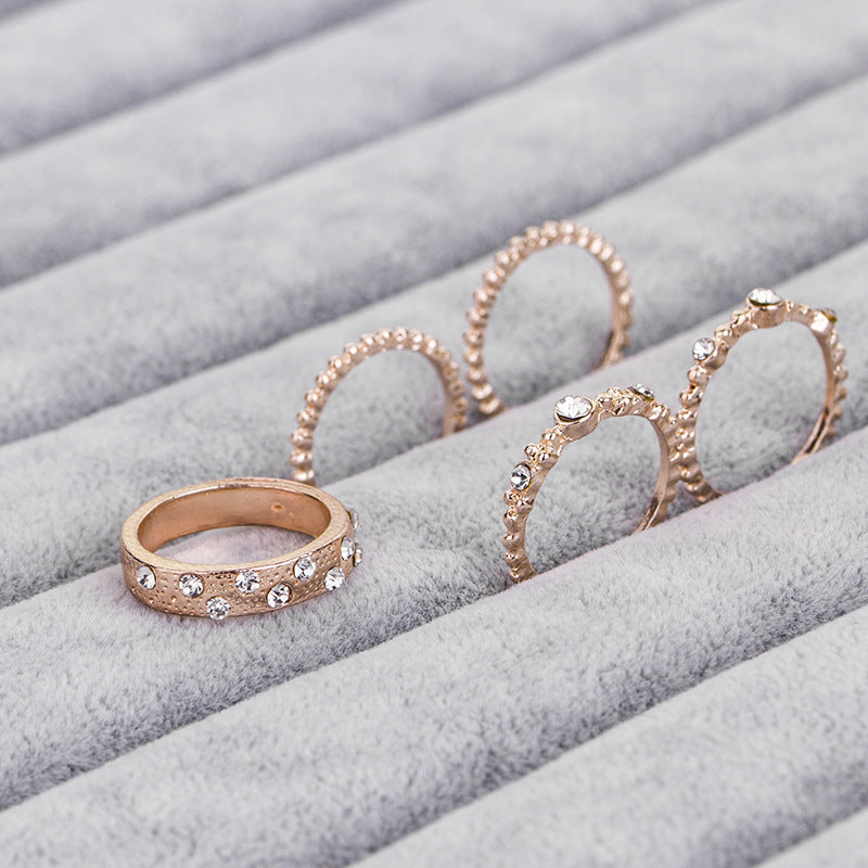 a group of gold rings with diamonds on a grey surface