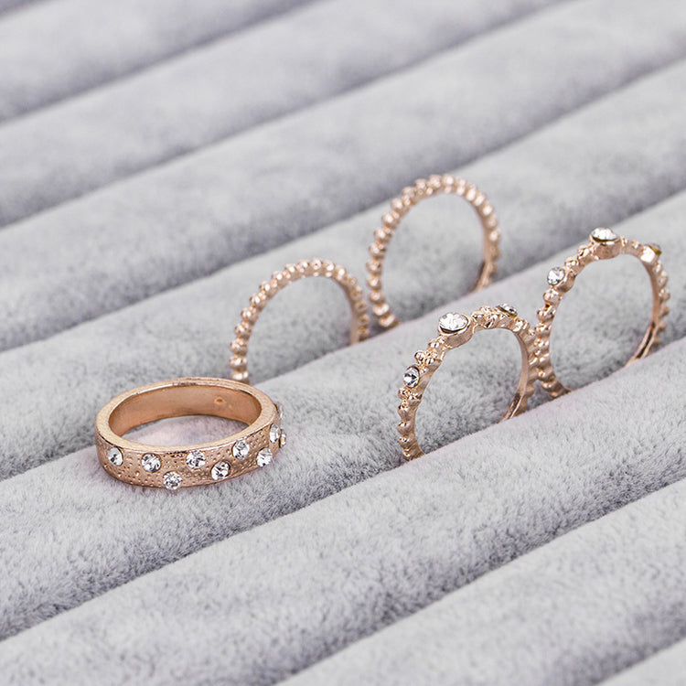 a group of gold rings with diamonds on a grey surface