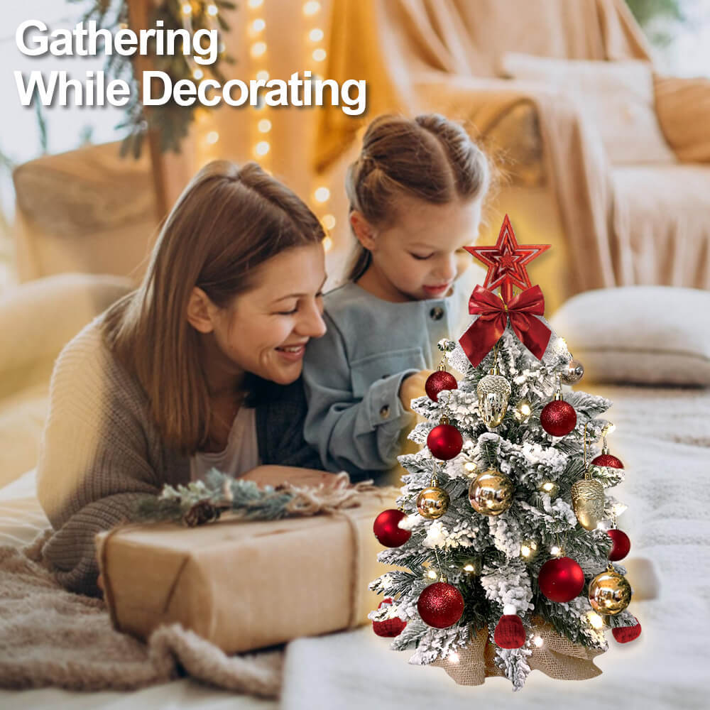 a woman and a girl lying on a bed next to a small christmas tree