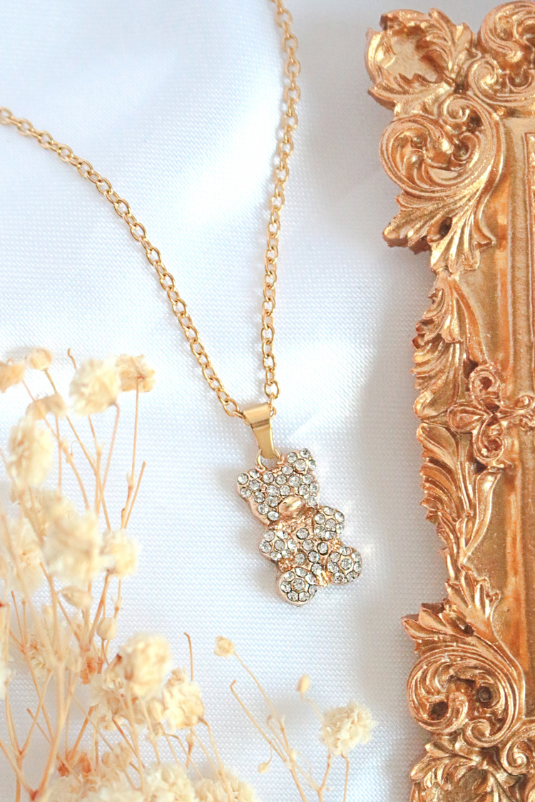 a gold necklace with a bear pendant and a picture frame
