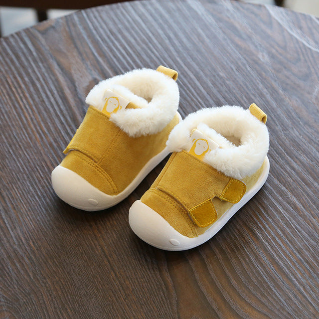 a pair of yellow baby shoes on a table