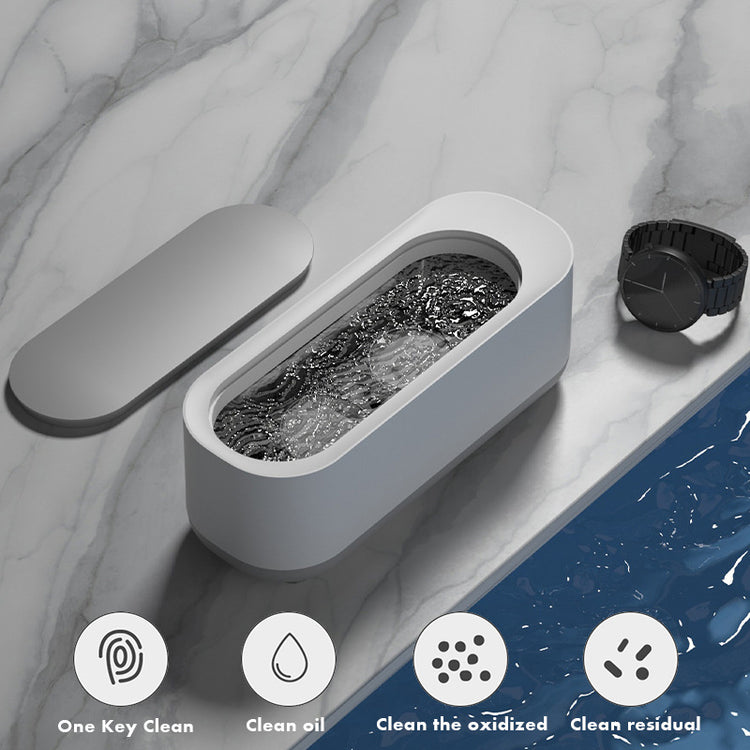 a white rectangular container with a black watch and a watch on a marble surface