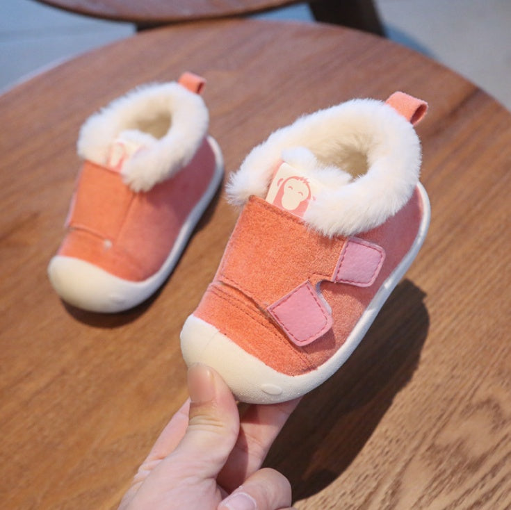 a hand holding a pair of pink shoes