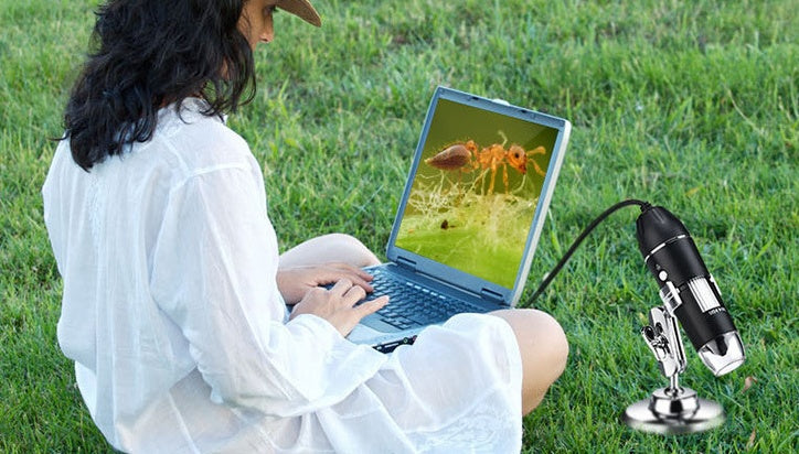 a woman sitting on grass using a laptop
