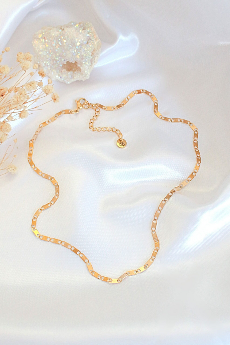 a gold chain necklace on a white fabric
