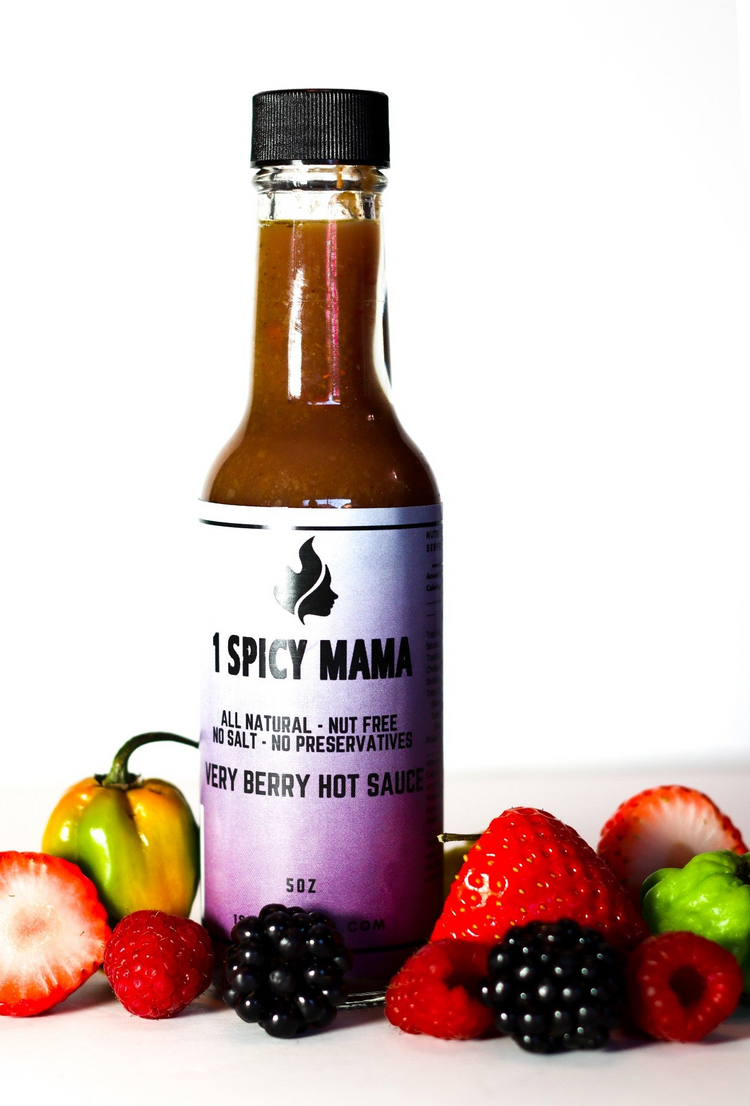 a bottle of hot sauce next to a pile of fruits
