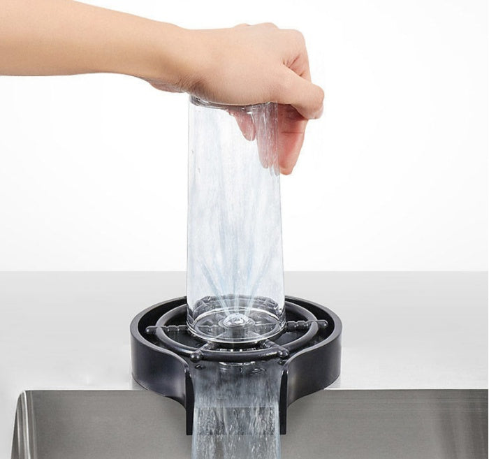 a hand holding a glass over a black container