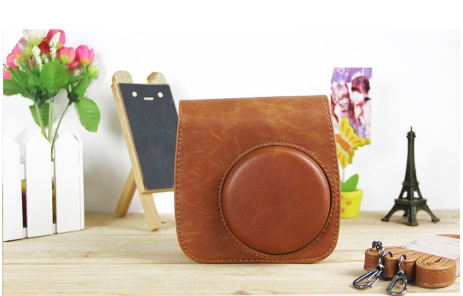 a brown leather case with a camera case and other objects on a table
