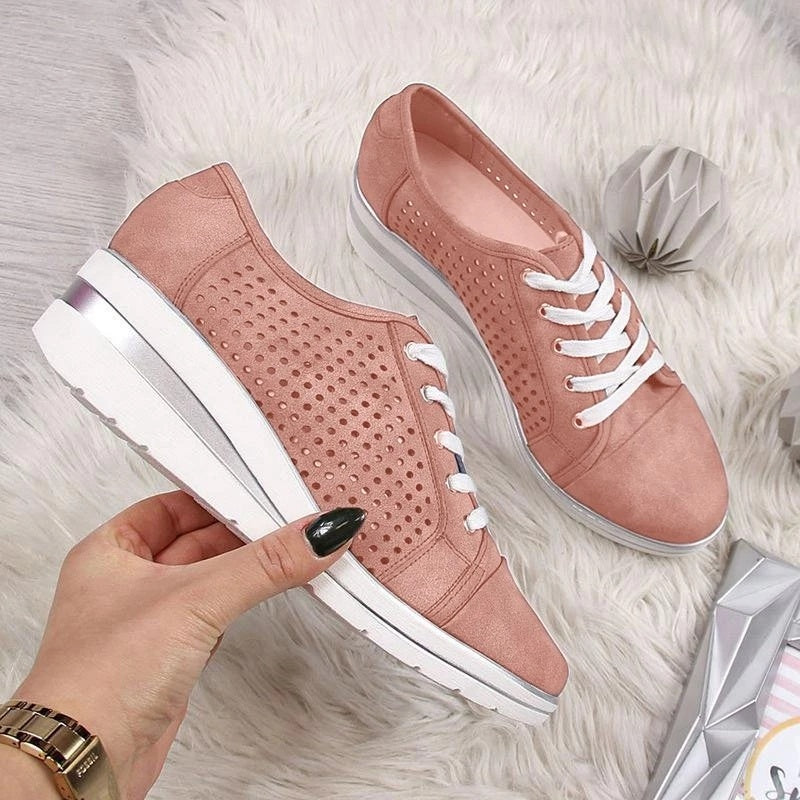 a hand holding a pair of pink shoes