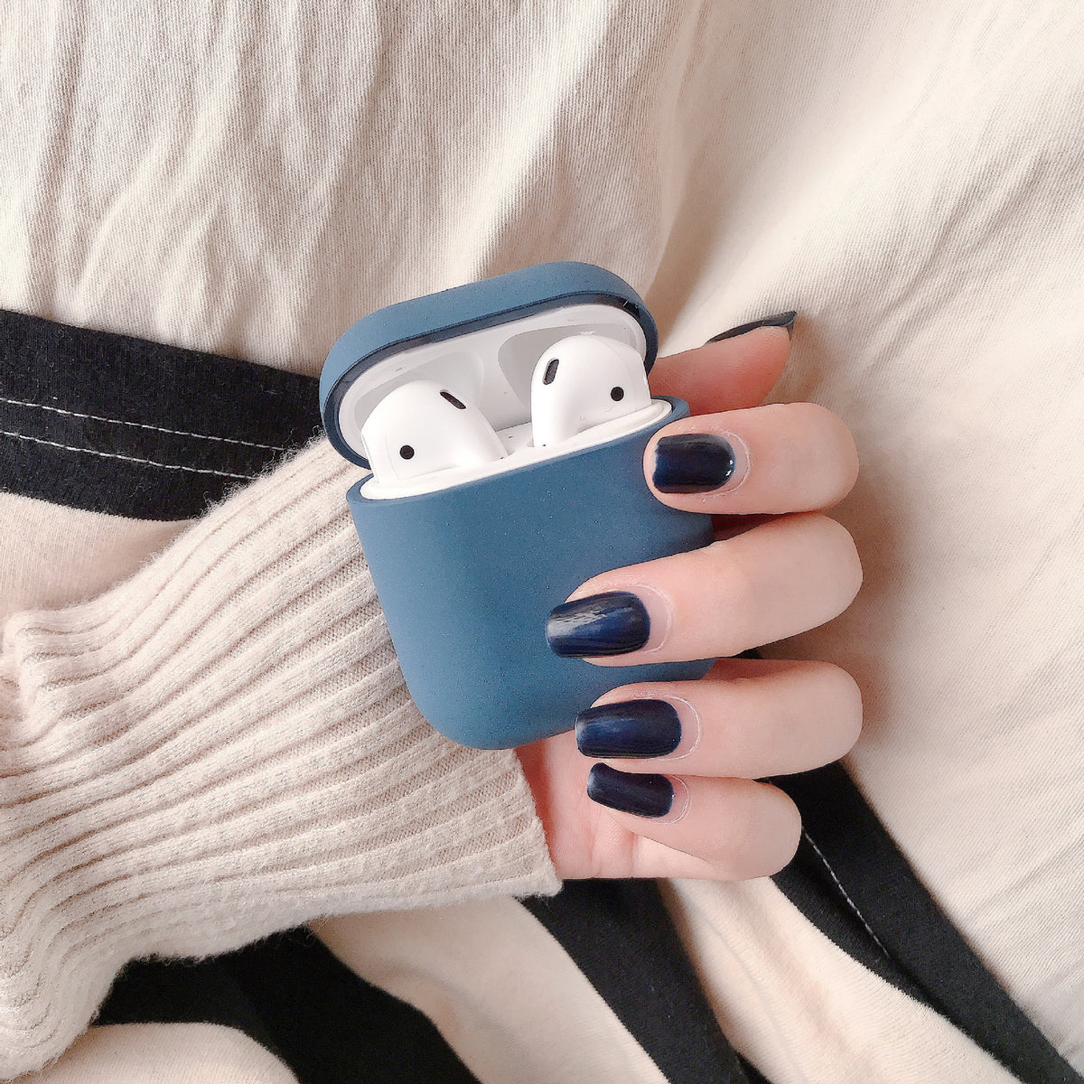 a hand holding a blue case with white ear buds