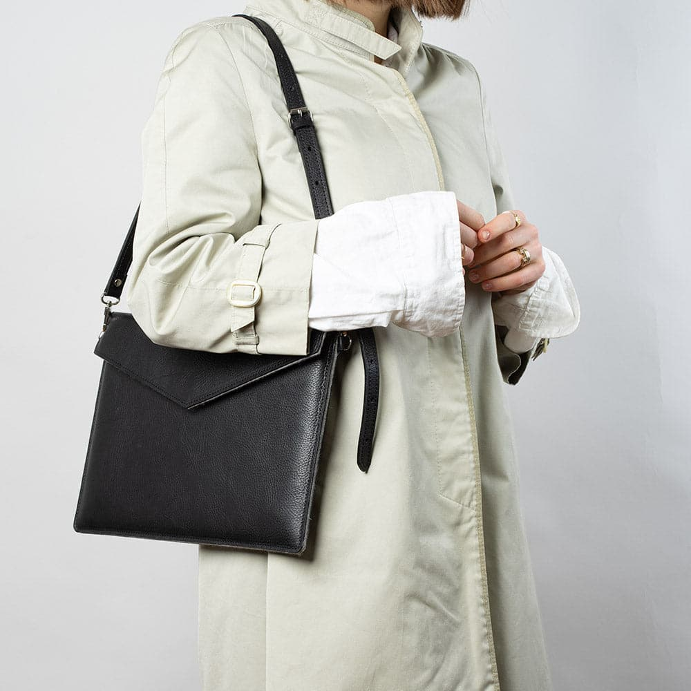 a woman in a white coat holding a black purse