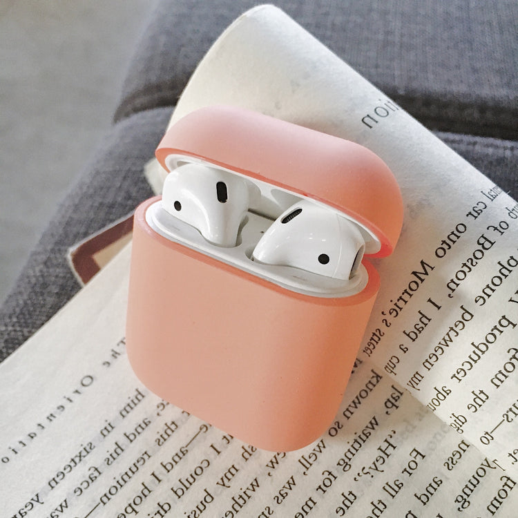 a pink case with white earbuds in it on a book