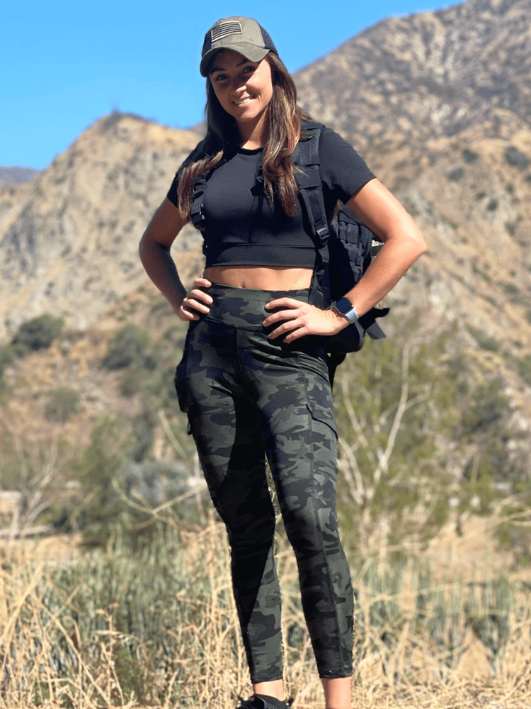 a woman standing in a field with mountains in the background