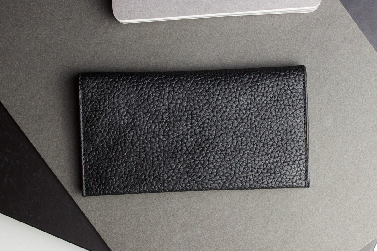 a black leather wallet on a grey surface