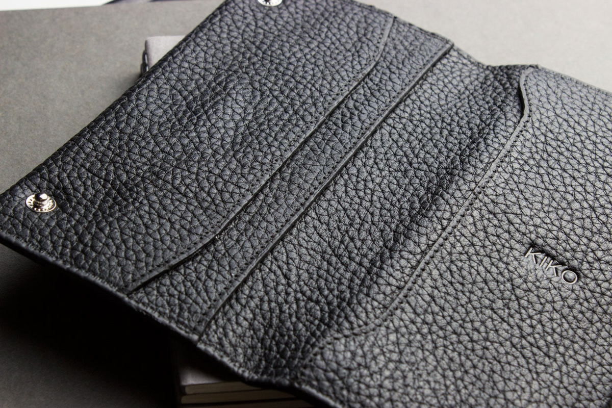 a black leather wallet on top of a stack of books