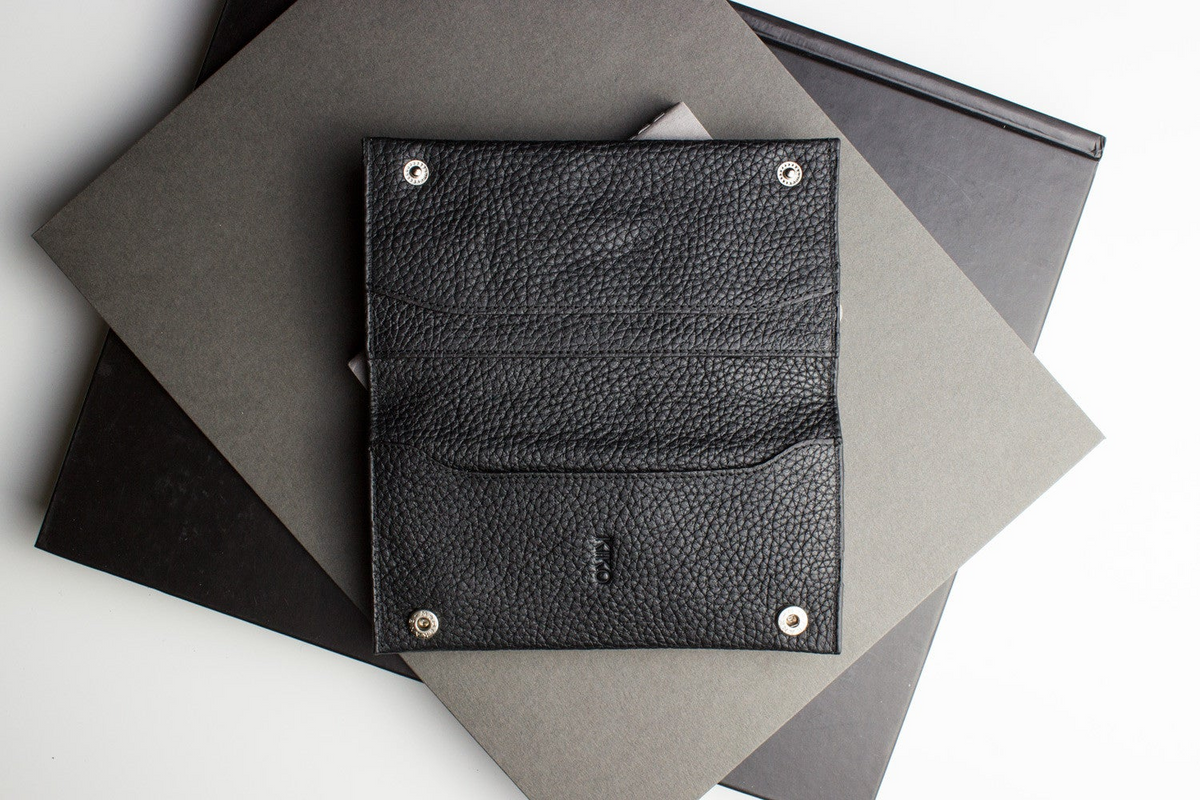 a black leather wallet on top of a stack of grey and black papers