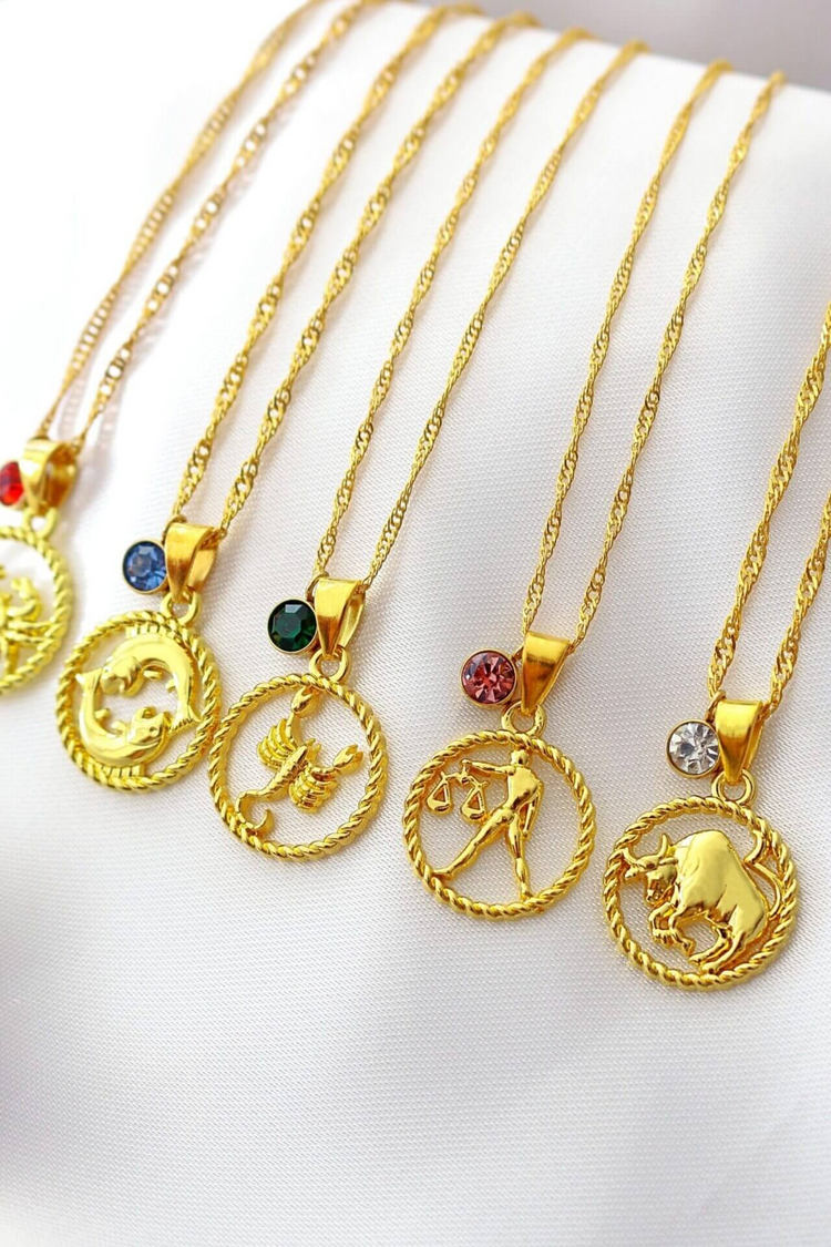 a group of gold necklaces with zodiac symbols