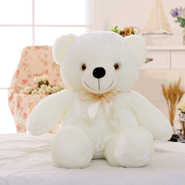 a white teddy bear on a bed