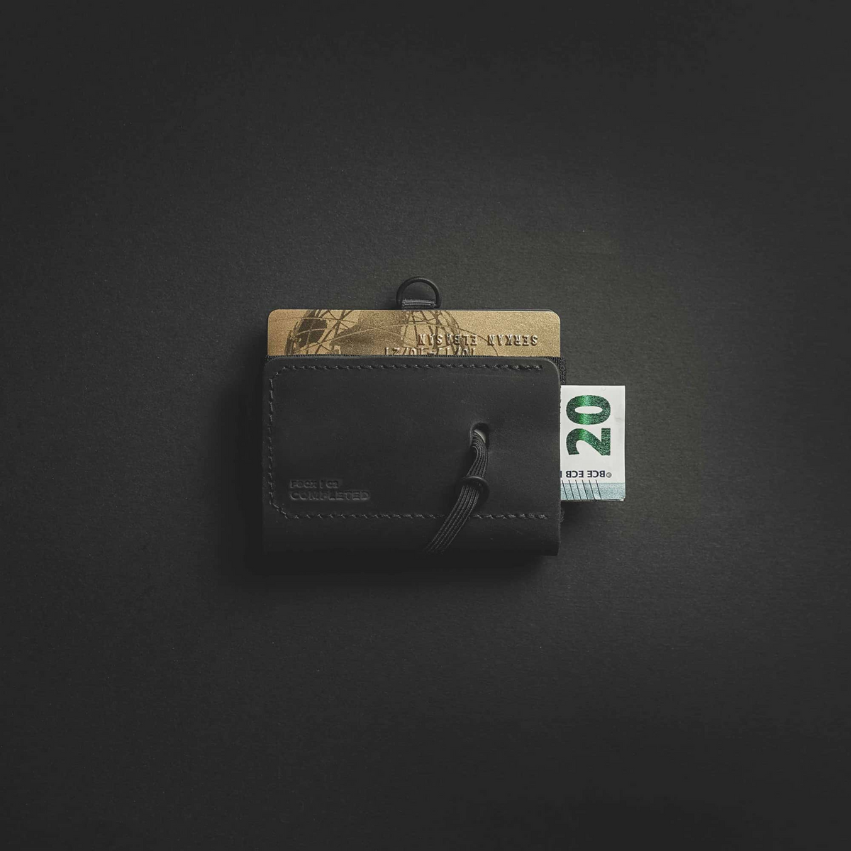 a black wallet with a gold and silver card and a money clip