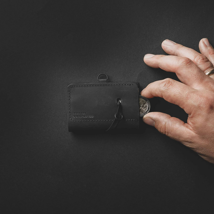 a hand putting a coin into a wallet