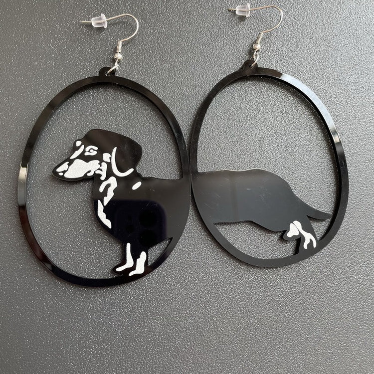 a pair of black earrings with a dog in the middle