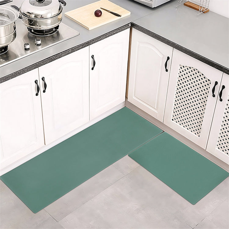 a kitchen with white cabinets and green mat