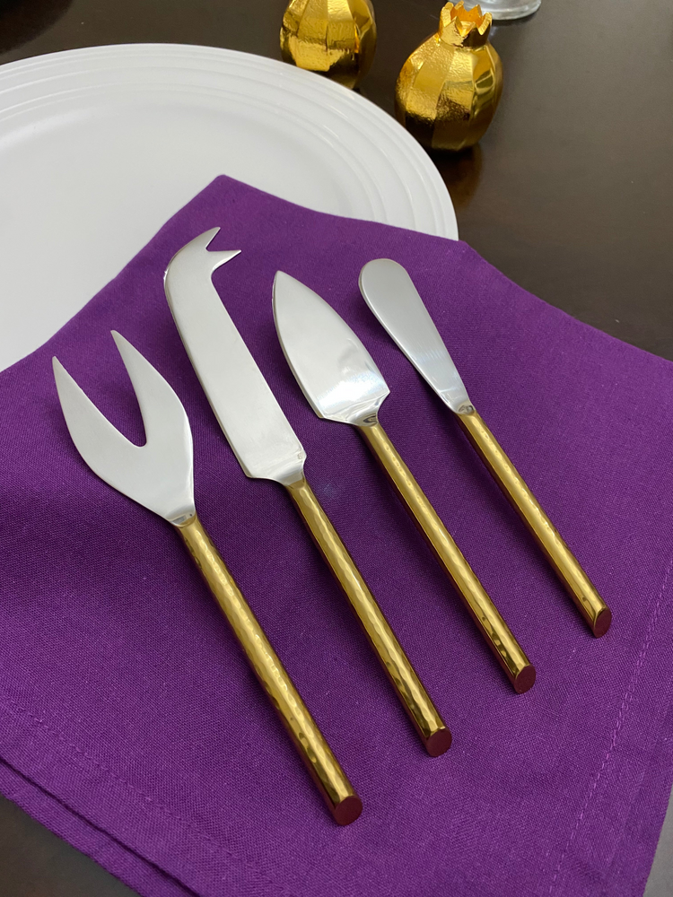 a group of silver knives on a purple napkin