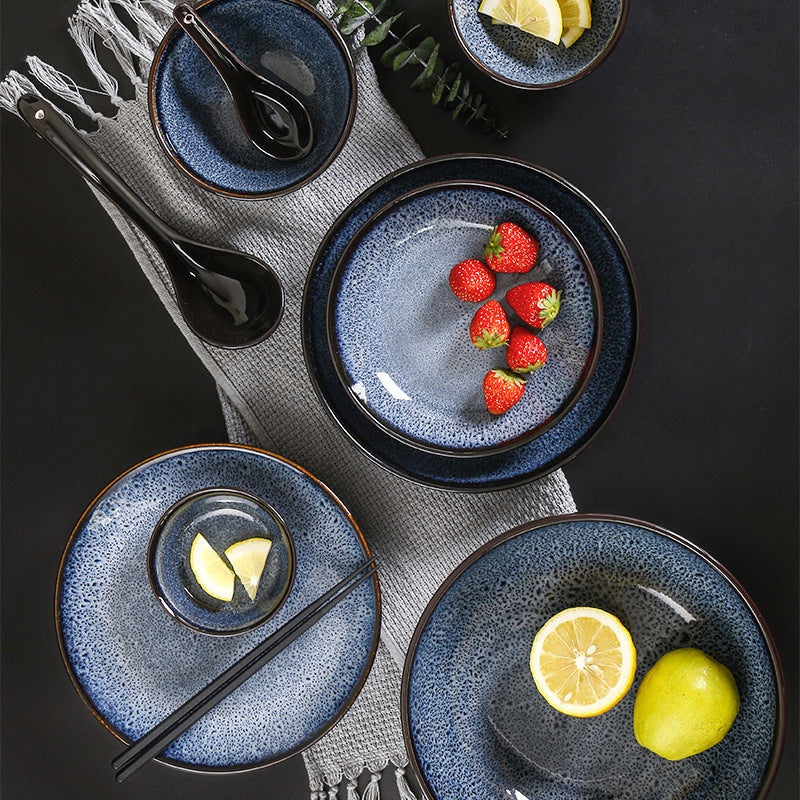 a group of blue plates and bowls with fruit and spoons