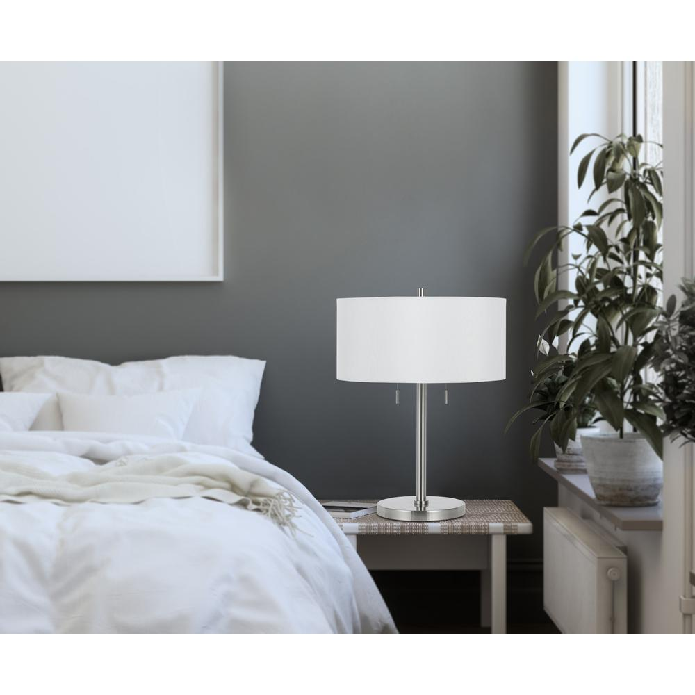 a lamp on a table next to a bed