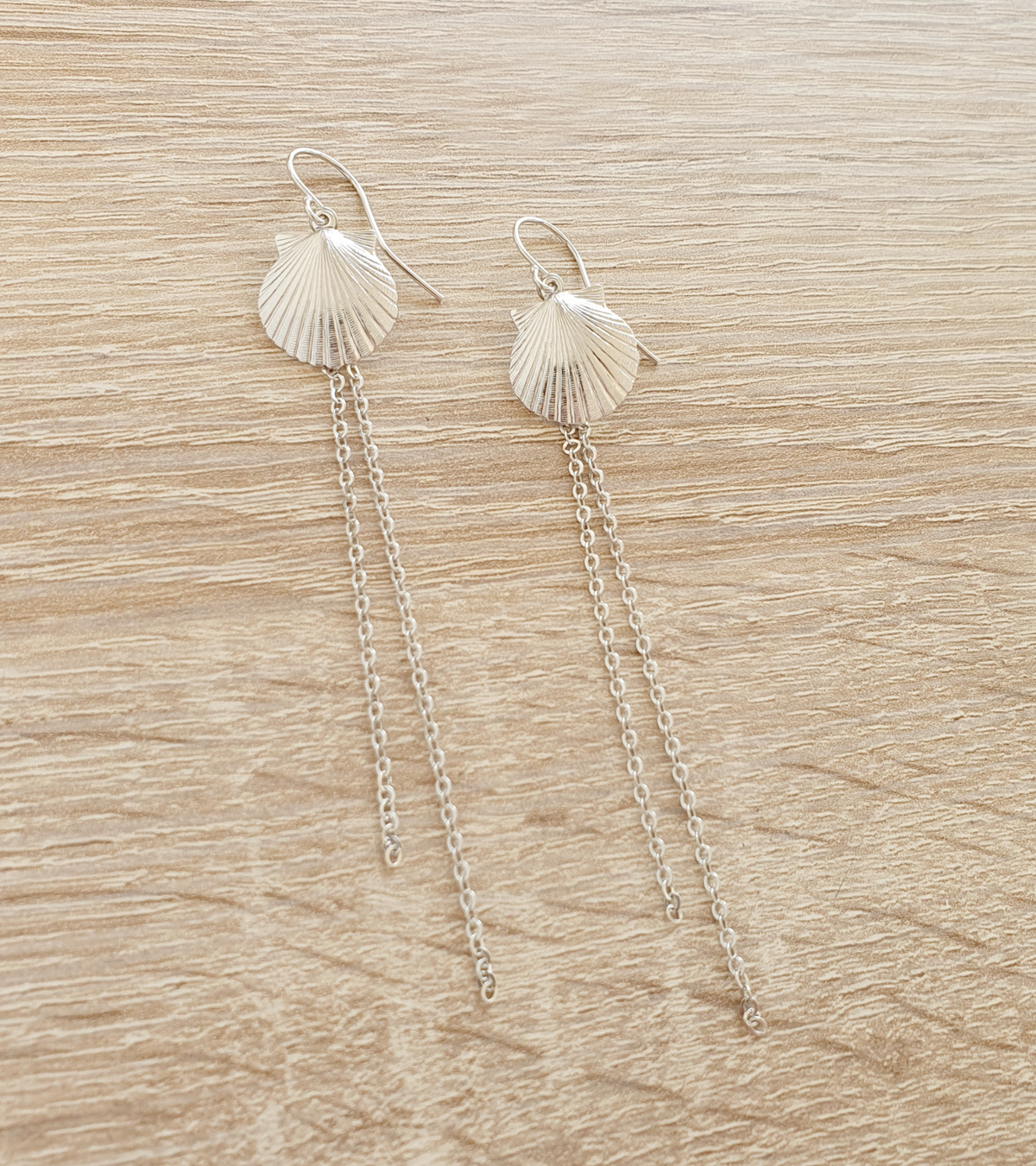 a pair of earrings on a wood surface