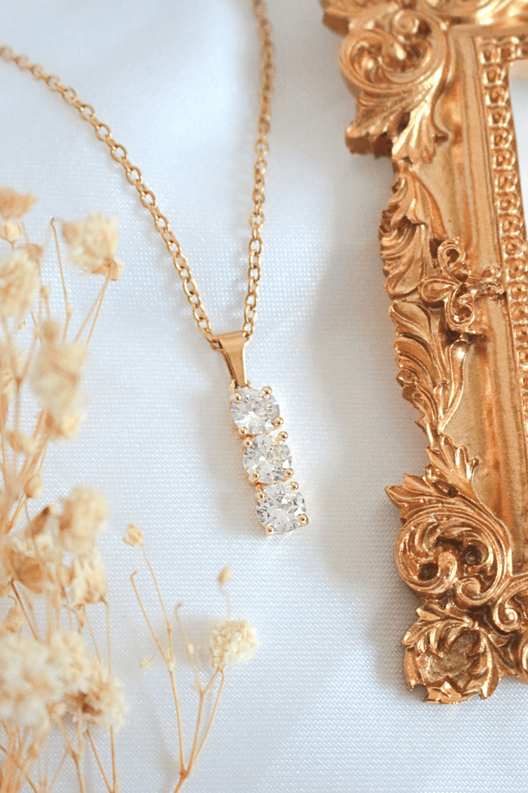 a gold necklace with diamonds on it next to a picture frame