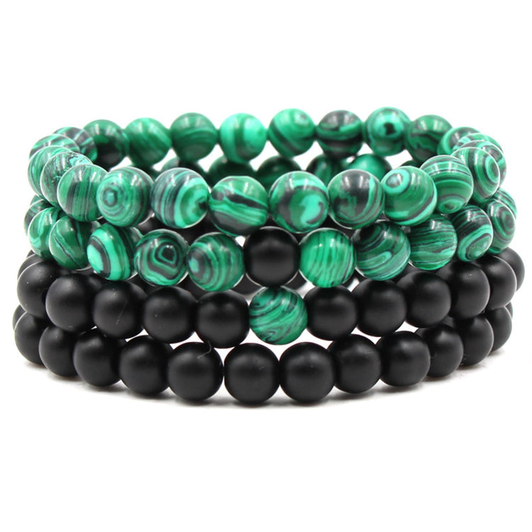a stack of bracelets with green and black beads