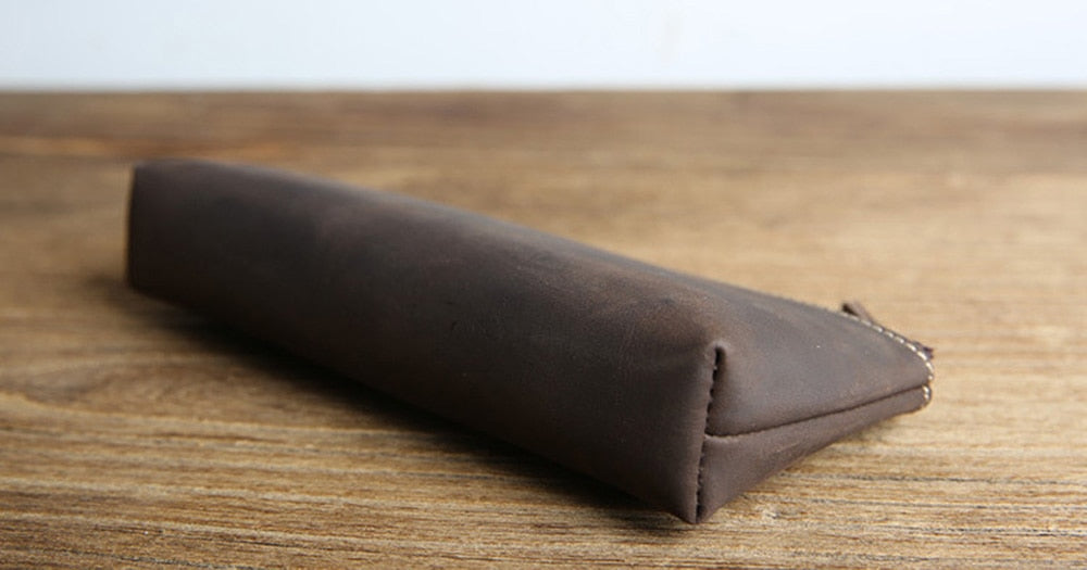 a brown leather bag on a wooden surface