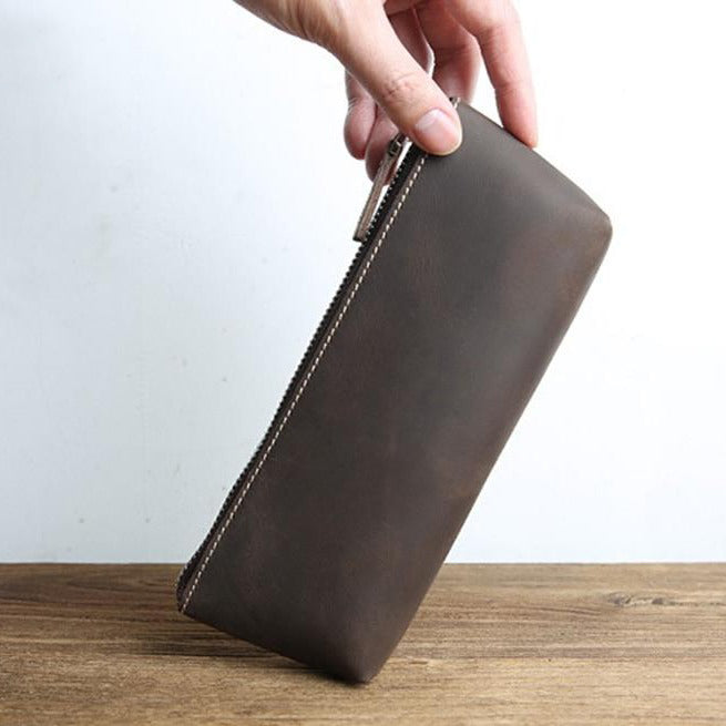 a hand holding a brown wallet