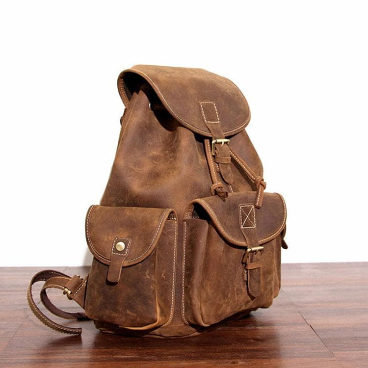 a brown leather backpack on a wood surface