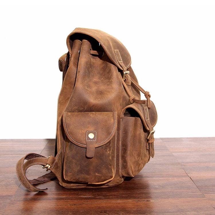 a brown leather backpack on a wood surface