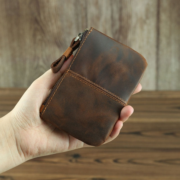 a hand holding a brown wallet