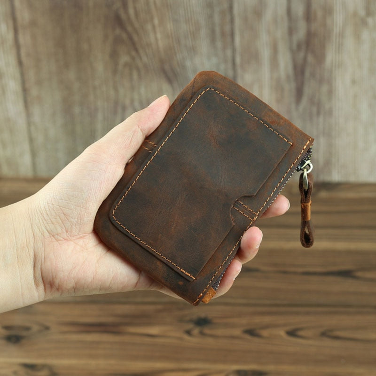 a hand holding a brown wallet