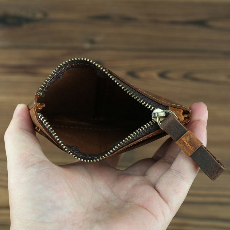 a hand holding a brown leather wallet