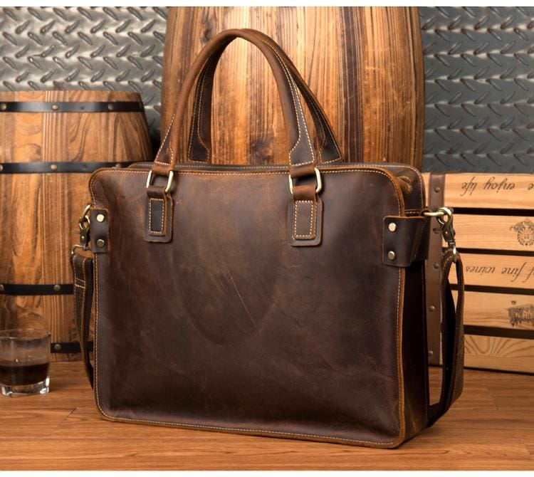 a brown leather bag with a glass of wine next to a barrel