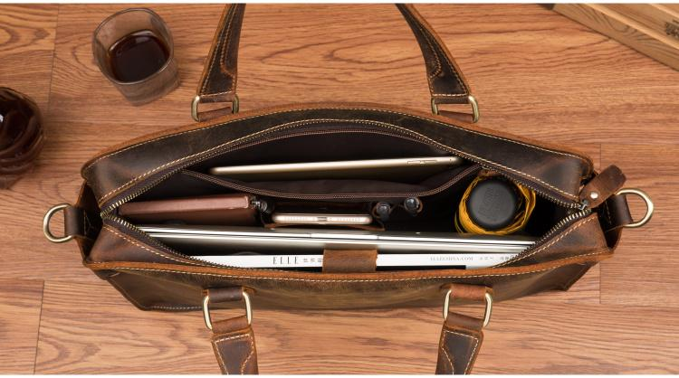 a brown leather bag with a laptop and other objects inside
